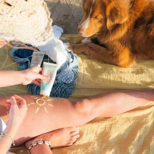 Mineral Sunscreen - Woman holding tube on beach - Suntribe Reef Safe Sunscreen-1-min (1)